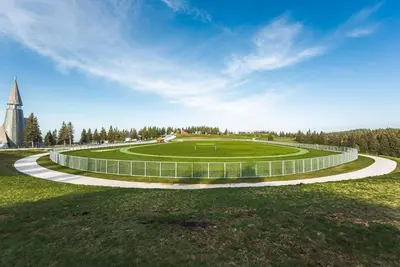 a circular green field with a clock tower in the distance at POHORJE HOUSE Rogla 2 in Oplotnica