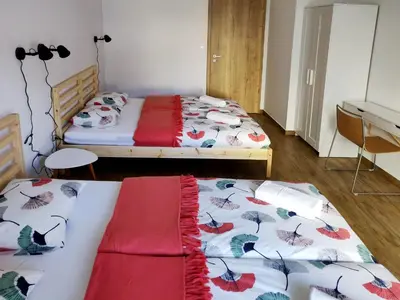 a bedroom with two beds and a table and a desk at PUBYLAND ROOMS & APARTMENTS in Rogatec