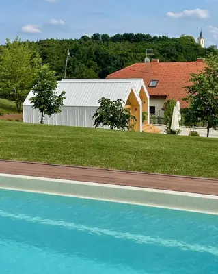 a building with a pool in front of a house at Domačija Pri Momi in Križevci