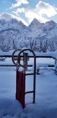 a chair in the snow with mountains in the background at Mountain peaks Apartment with Sauna in Gozd Martuljek
