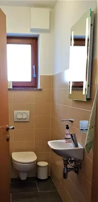 a bathroom with a sink and a toilet and a window at Mountain peaks Apartment with Sauna in Gozd Martuljek
