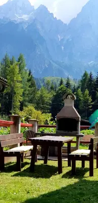 a picnic table and a gazebo with mountains in the background at Mountain peaks Apartment with Sauna in Gozd Martuljek