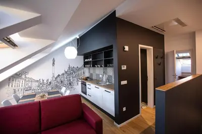 a living room with a red couch and a kitchen at Postcard City Apartments in Maribor