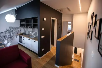 a living room with a red couch and a kitchen at Postcard City Apartments in Maribor