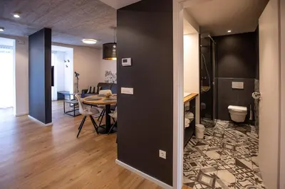 a room with a table and a bathroom with a toilet at Postcard City Apartments in Maribor