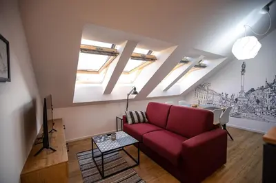 a living room with a red couch and a tv at Postcard City Apartments in Maribor