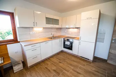 a kitchen with white cabinets and a wooden floor at Holiday Home Kerin in Cerklje ob Krki