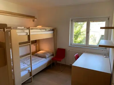 a small room with bunk beds and a desk and a window at Apartment MIMI in Kranjska Gora