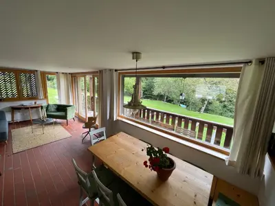 a room with a wooden table and a large window at Bohinj Barn in Bohinj