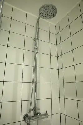 a shower head in a bathroom with white tiles at Apartma Verdi Bc in Bovec
