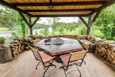 a patio with a table and chairs and a bunch of logs at Lake House with a View in Šmartno v Rožni Dolini