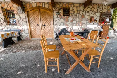a wooden table and chairs in front of a stone building at Authentic Countryside Villa with Hot tub in Veliki Kamen