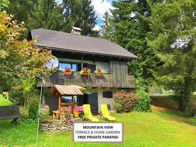 a house with a balcony with flowers on it at Peaceful Nature Cabin Jolly in Mozirje