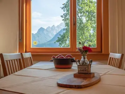 a dining room table with a view of a mountain at Alpeambient house Dovje in Mojstrana