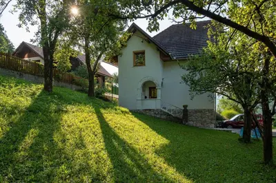 a white house on a grassy yard with trees at Alpeambient house Dovje in Mojstrana