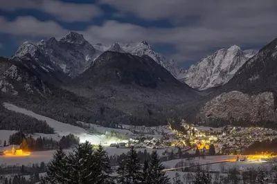 a town in a valley with snow capped mountains at Alpeambient house Dovje in Mojstrana