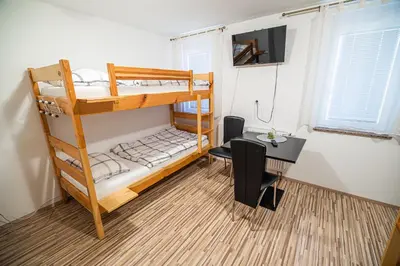 a room with two bunk beds and a desk and a table at Rooms at Trimček in Sevnica