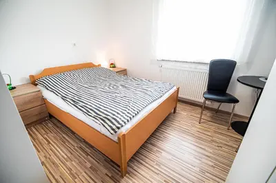 a small bedroom with a bed and a chair at Rooms at Trimček in Sevnica