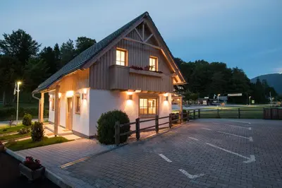 a building with a balcony on a parking lot at Apartments Alp in Bohinj