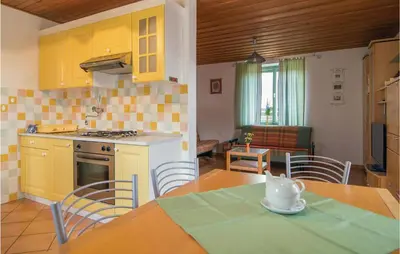 a kitchen with yellow cabinets and a table with chairs at 4 Bedroom Lovely Home In Kostel in Kupa
