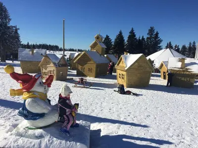 a child is sitting on a snowman in the snow at Tree Top Rogla Apartment in Zreče