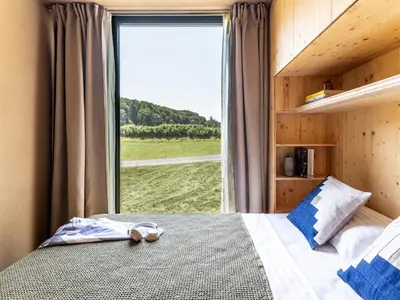 a bedroom with a bed with a large window at Falkensteiner Premium Camping Lake Blagus in Sveti Jurij ob Ščavnici