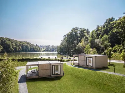 two mobile homes in the grass next to a lake at Falkensteiner Premium Camping Lake Blagus in Sveti Jurij ob Ščavnici