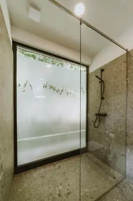 a glass shower in a room with a window at Falkensteiner Premium Camping Lake Blagus in Sveti Jurij ob Ščavnici