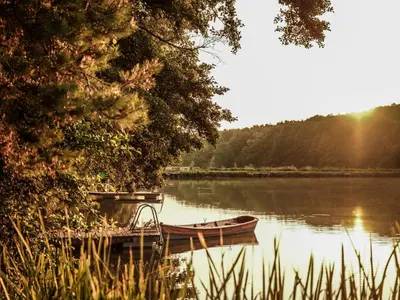 a boat is docked on a lake with the sunset at Falkensteiner Premium Camping Lake Blagus in Sveti Jurij ob Ščavnici