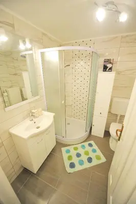 a white bathroom with a sink and a shower at Apartments Jernej with Onsite Wellness in Brežice