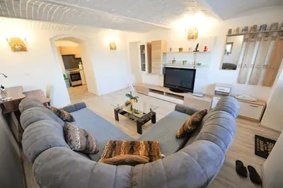 a living room with a large couch and a television at Apartments Jernej with Onsite Wellness in Brežice