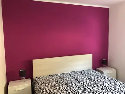 a bedroom with a purple wall and a bed at APARTMA CARPE DIEM in Kranjska Gora
