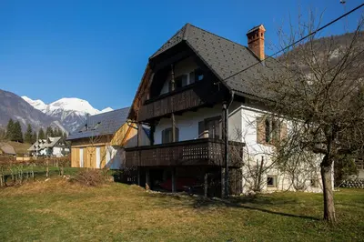 a large house with a balcony and mountains in the background at Magical Family Home 84 in Bohinj
