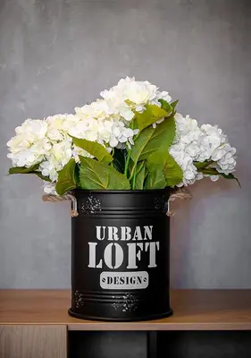 a black container filled with white flowers on a table at Urban Ring Hotel in Ljubljana