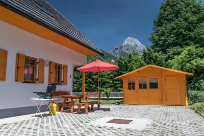 a patio with a table and an umbrella and a shed at House Parabola in Log pod Mangartom