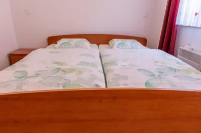 a bed with a wooden bed frame and a bedspread at House Parabola in Log pod Mangartom