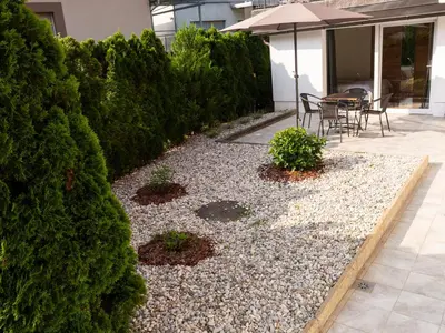 a garden with two chairs and a table with an umbrella at D&N Apartment in Ljubljana