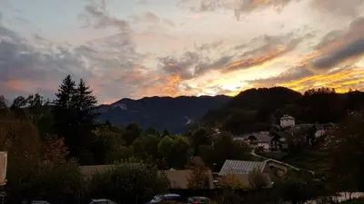 a sunset over a town with mountains in the background at ALEX BUMBLEBEE in Bled