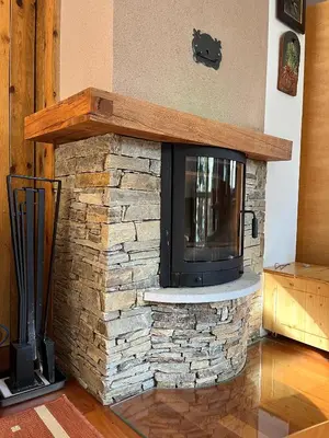 a stone fireplace with a tv on top of it at Chalet Harmony Rogla - apartment in Zreče