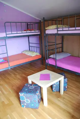 a room with three bunk beds and a table at Hostel Ociski Raj in Kozina