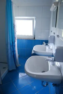 a blue and white bathroom with a sink and a window at Hostel Ociski Raj in Kozina