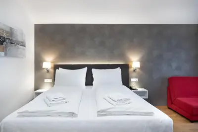 a bedroom with a large bed and a red couch at Hotel Dvorec in Tolmin