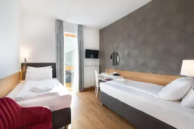 a hotel room with two beds and a red chair at Hotel Dvorec in Tolmin