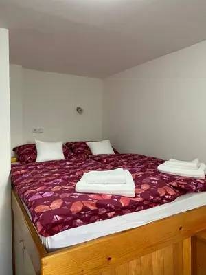a bed with a purple comforter and white towels on it at Apartma Bernard in Radovljica