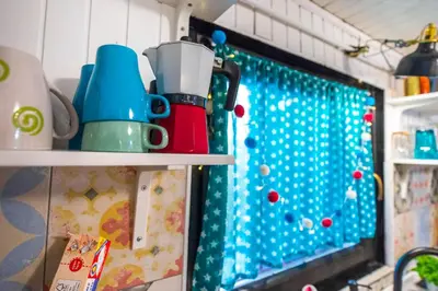 a kitchen shelf with cups and a christmas window at Boho House 1 camp Terme Catez with promotional tickets prices in Čatež ob Savi