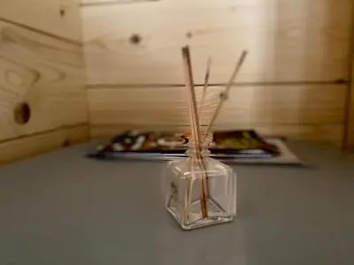 a glass vase with sticks in it on a table at Wooden lodge with jacuzzi in Rečica ob Savinji