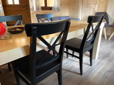 a dining room table with two black chairs around it at Wooden lodge with jacuzzi in Rečica ob Savinji