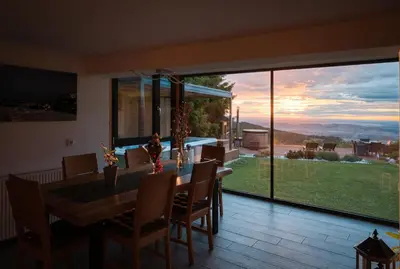 a dining room with a table and a large window at Panoramic View Cottage Heated Pool, Swimspa & Sauna in Pohorje