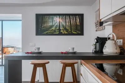 a kitchen with two stools and a picture on the wall at Panoramic View Cottage Heated Pool, Swimspa & Sauna in Pohorje