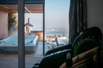 a room with a tub and a view of the ocean at Panoramic View Cottage Heated Pool, Swimspa & Sauna in Pohorje